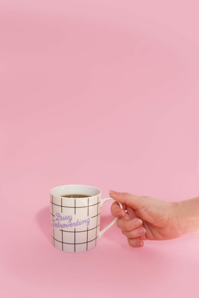 hand holding mug that says busy introverting